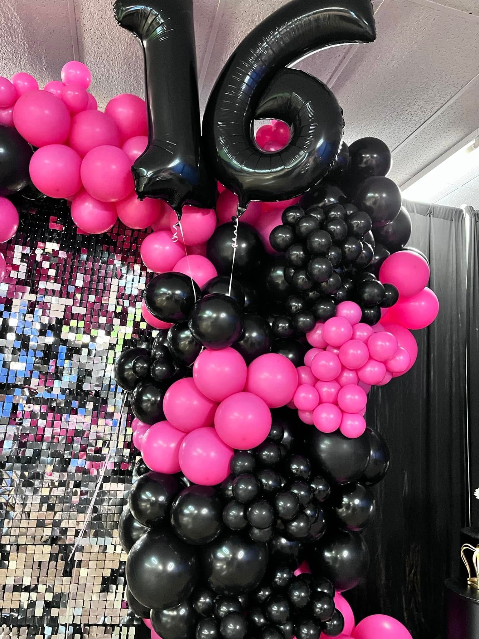 A bunch of pink and black balloons with the number 16 on top of them.