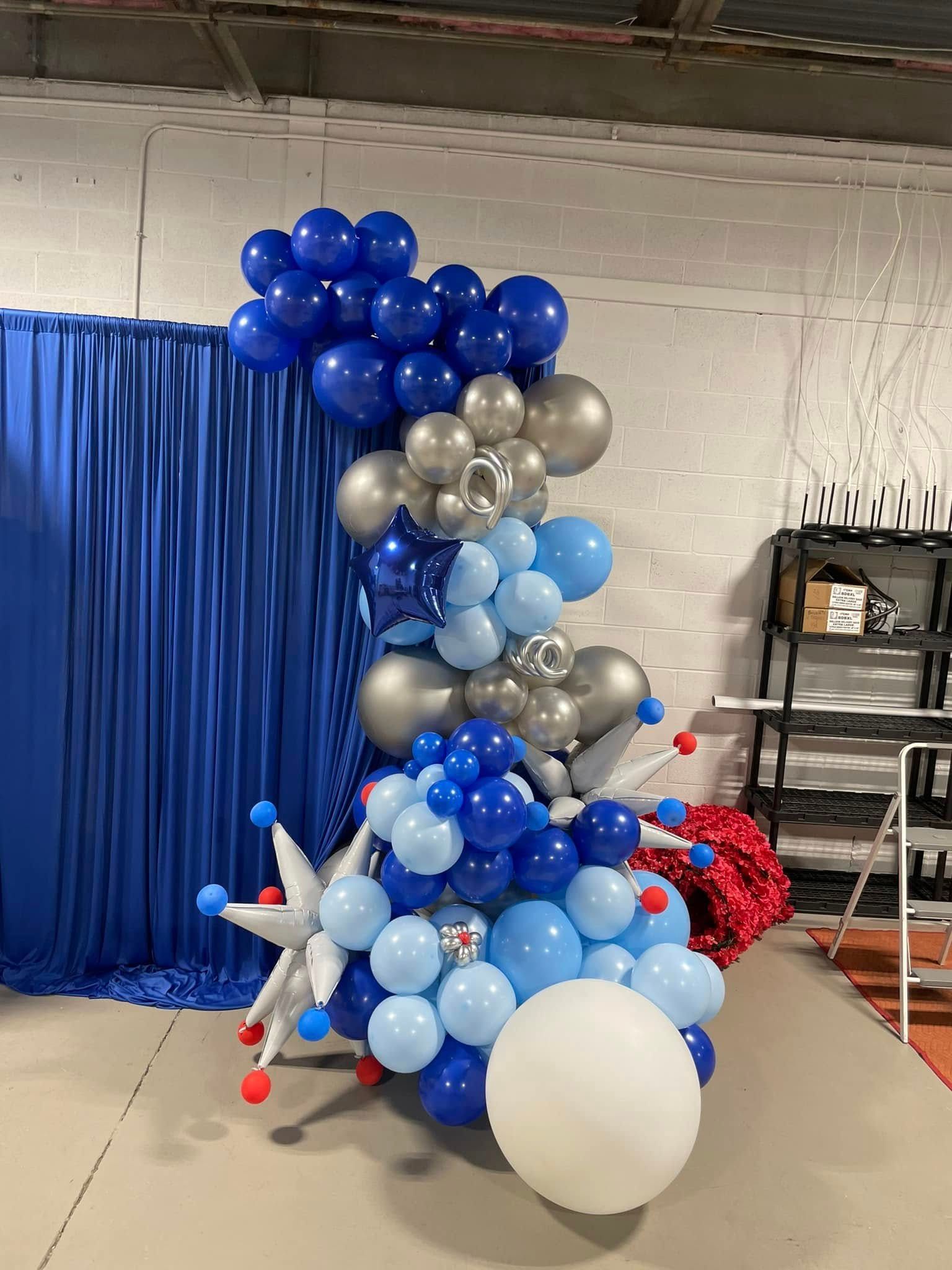 A bunch of blue and silver balloons are sitting on the floor in a room.