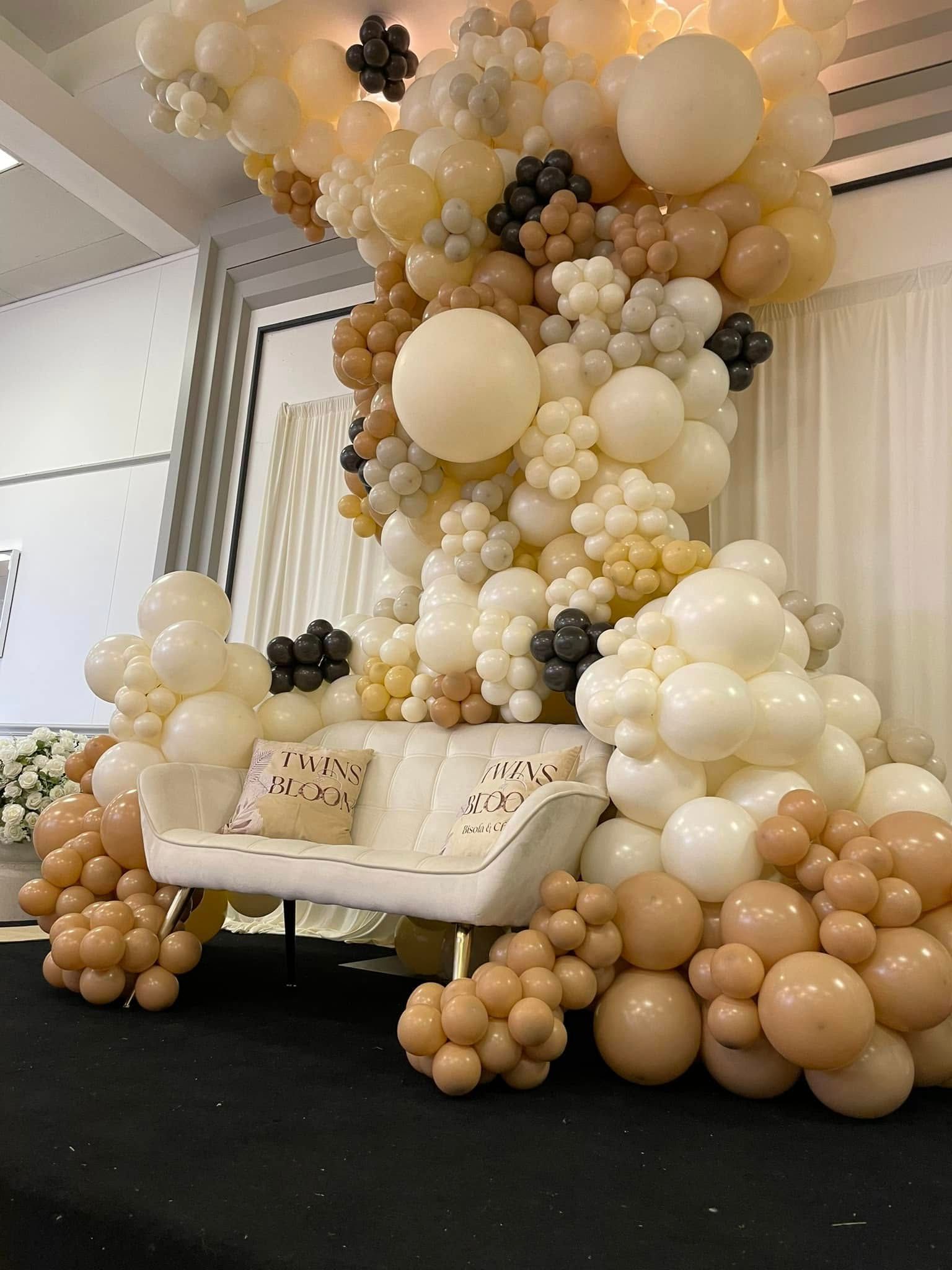 A couch is surrounded by balloons on a stage.
