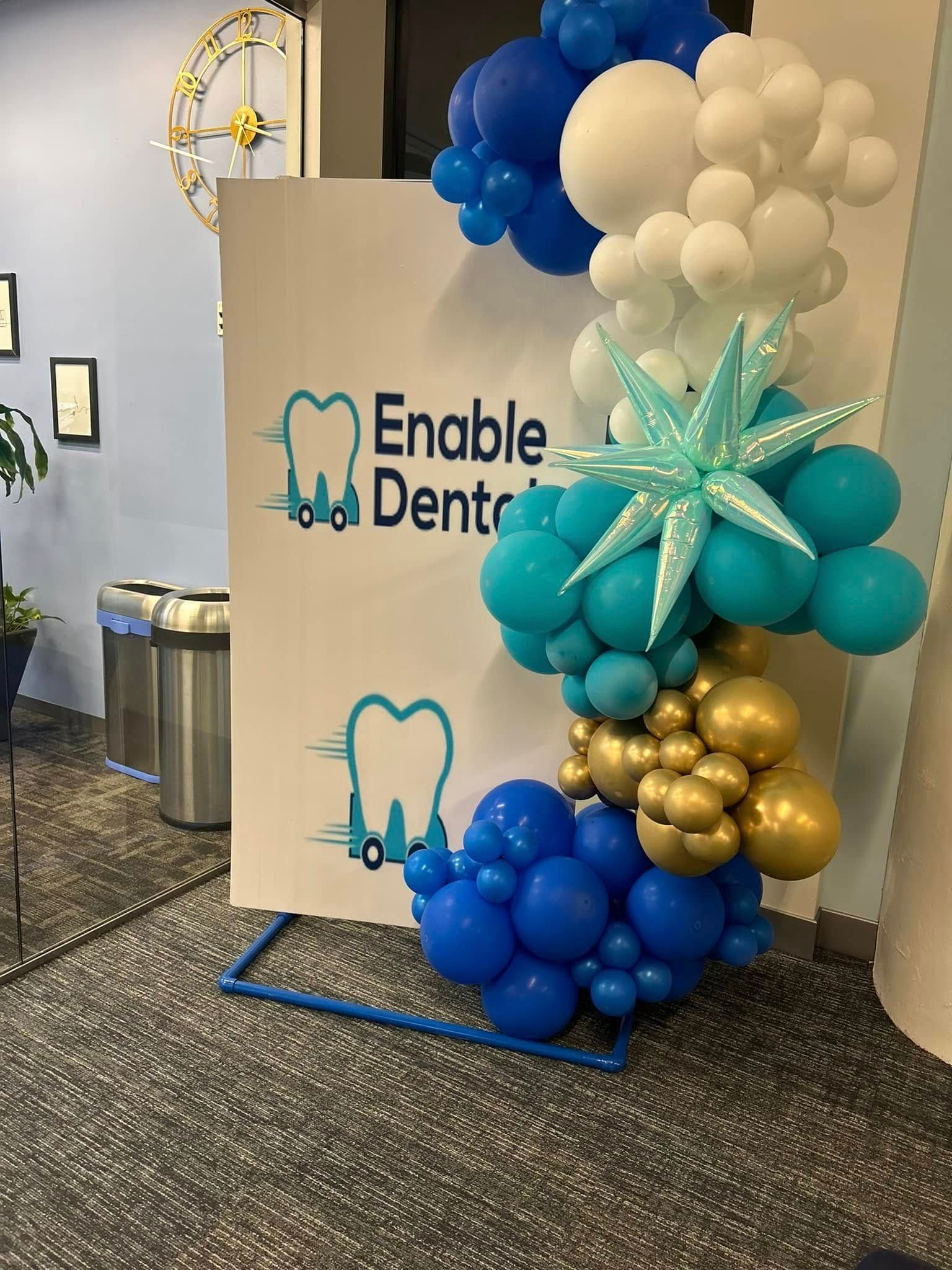 A bunch of balloons are sitting in front of a sign that says `` enable dental ''.