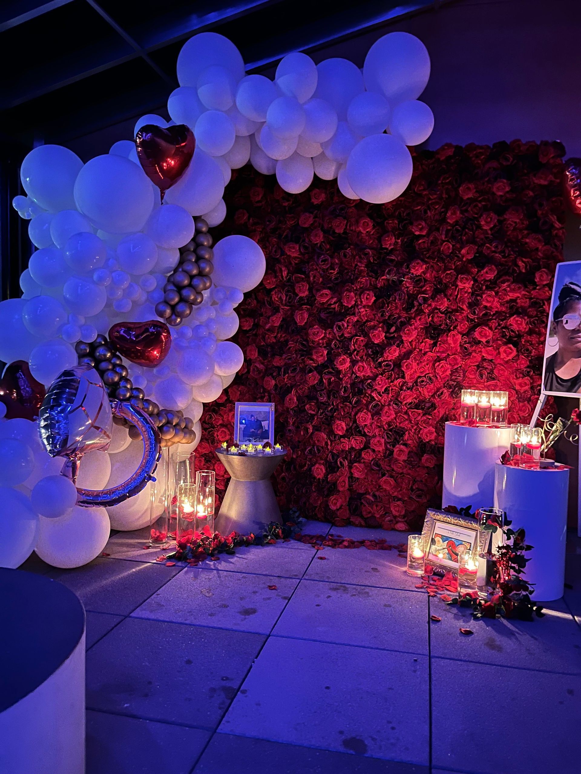 A room filled with balloons , flowers and candles.