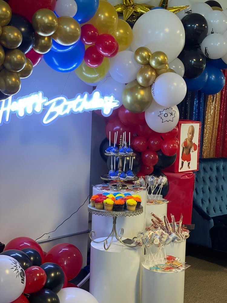 A room filled with balloons and a neon sign that says happy birthday