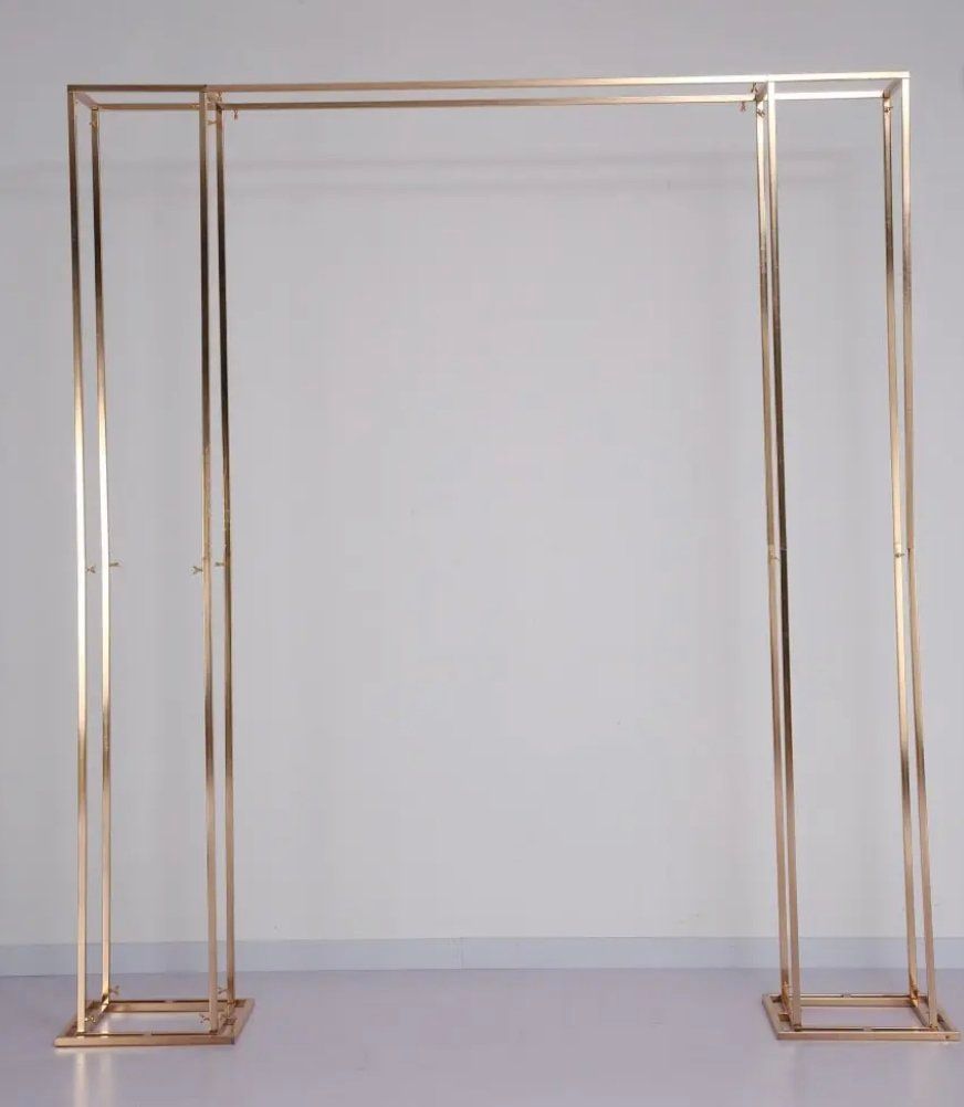 A gold metal arch is sitting in front of a white wall.