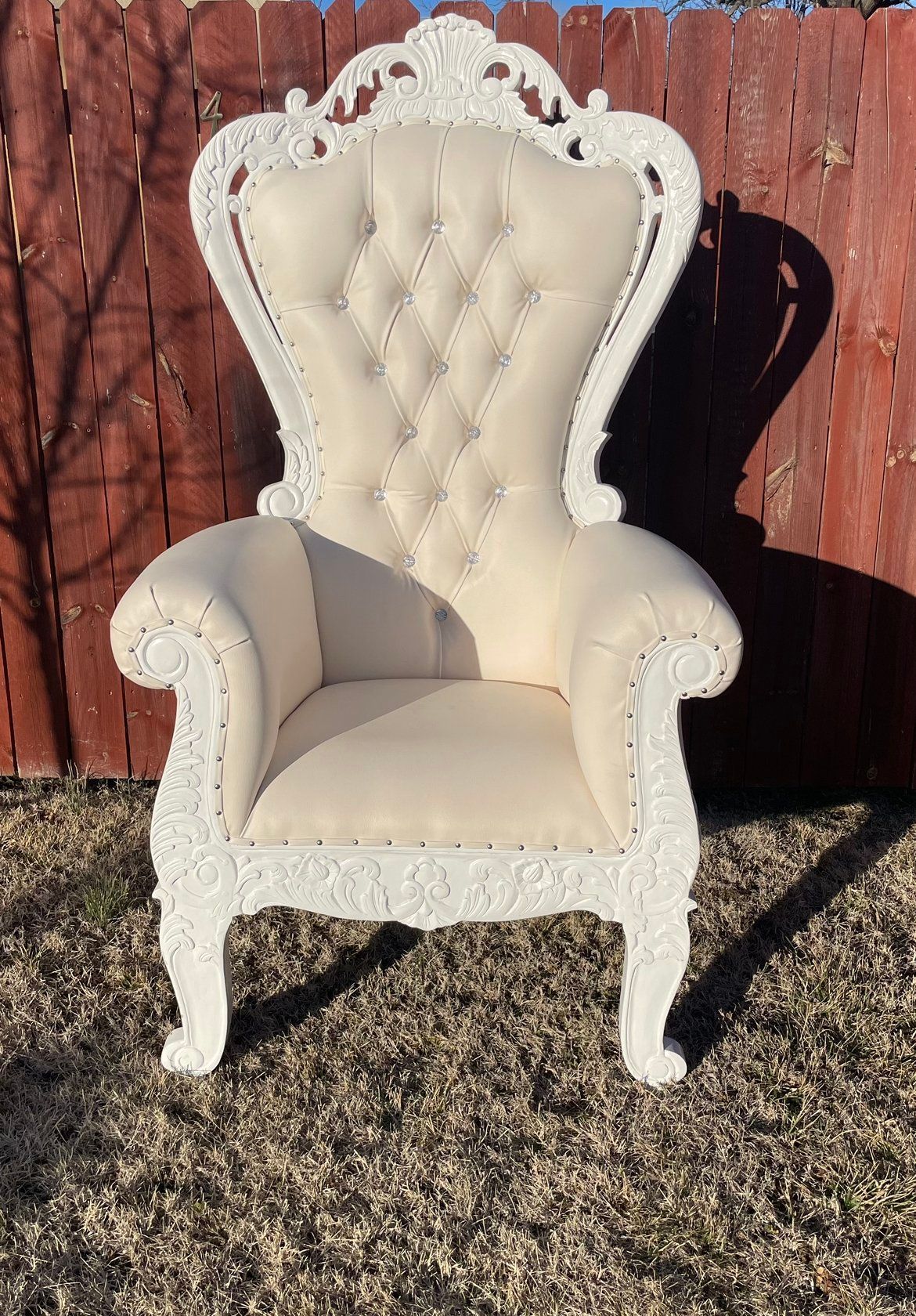 A white chair is sitting in front of a wooden fence.