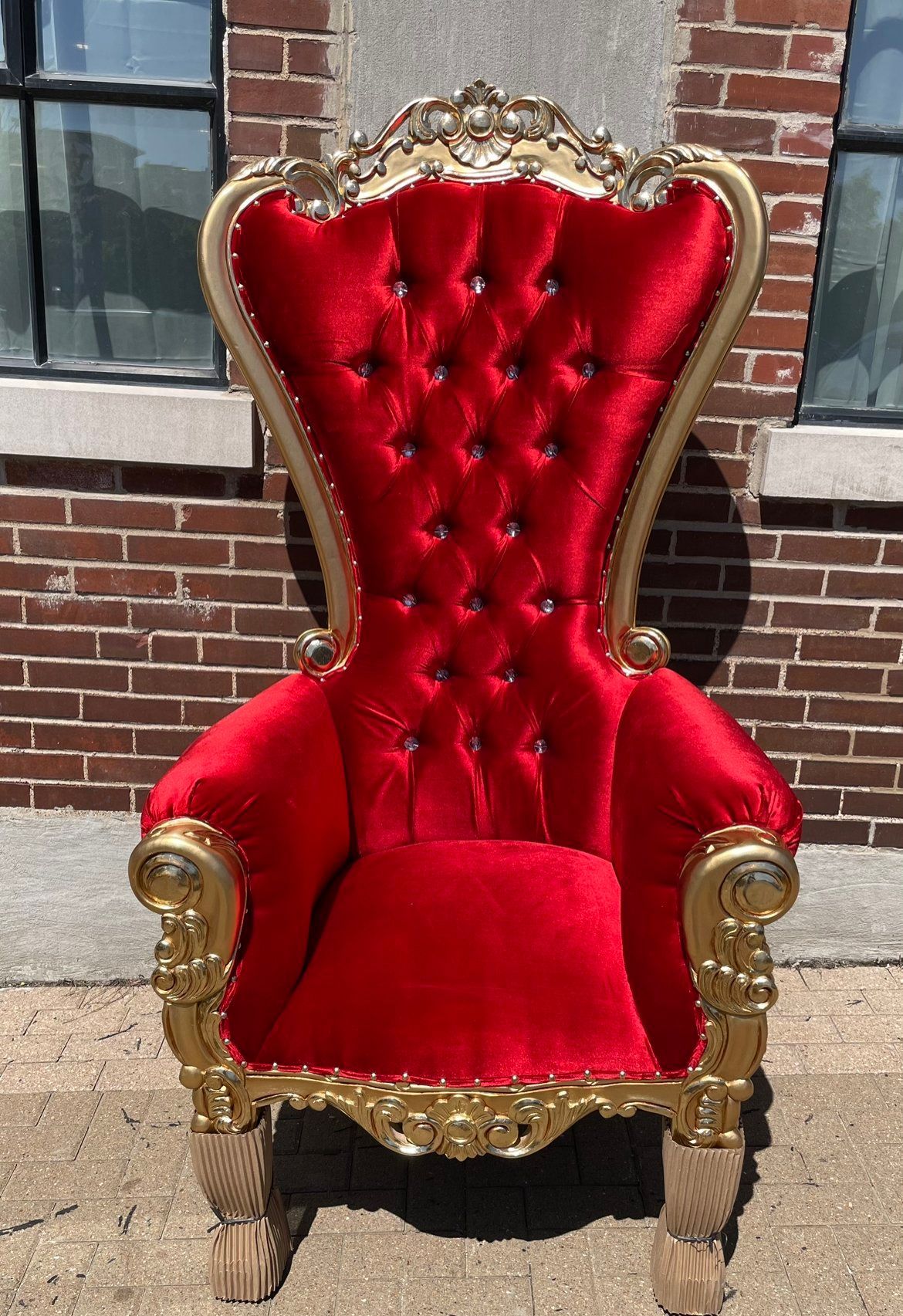 A red and gold chair is sitting in front of a brick building.