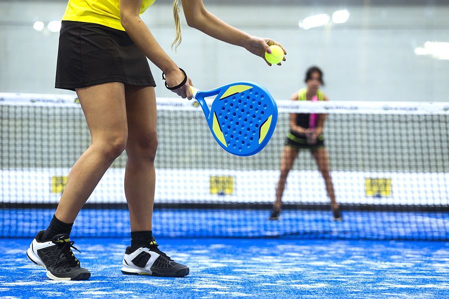 A woman is playing paddle tennis on a blue court