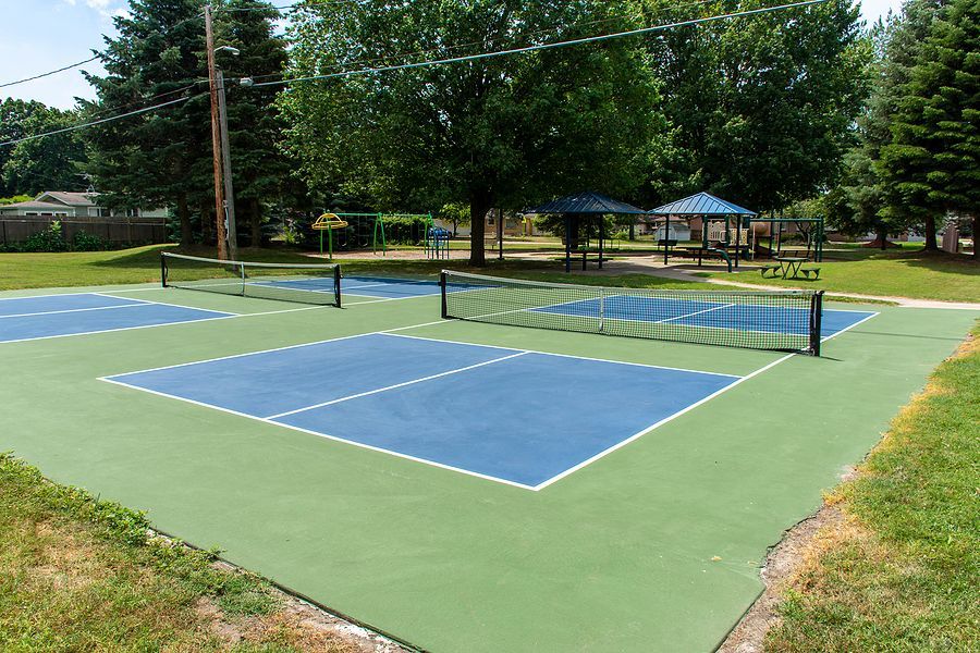 A tennis court in a park with trees in the background