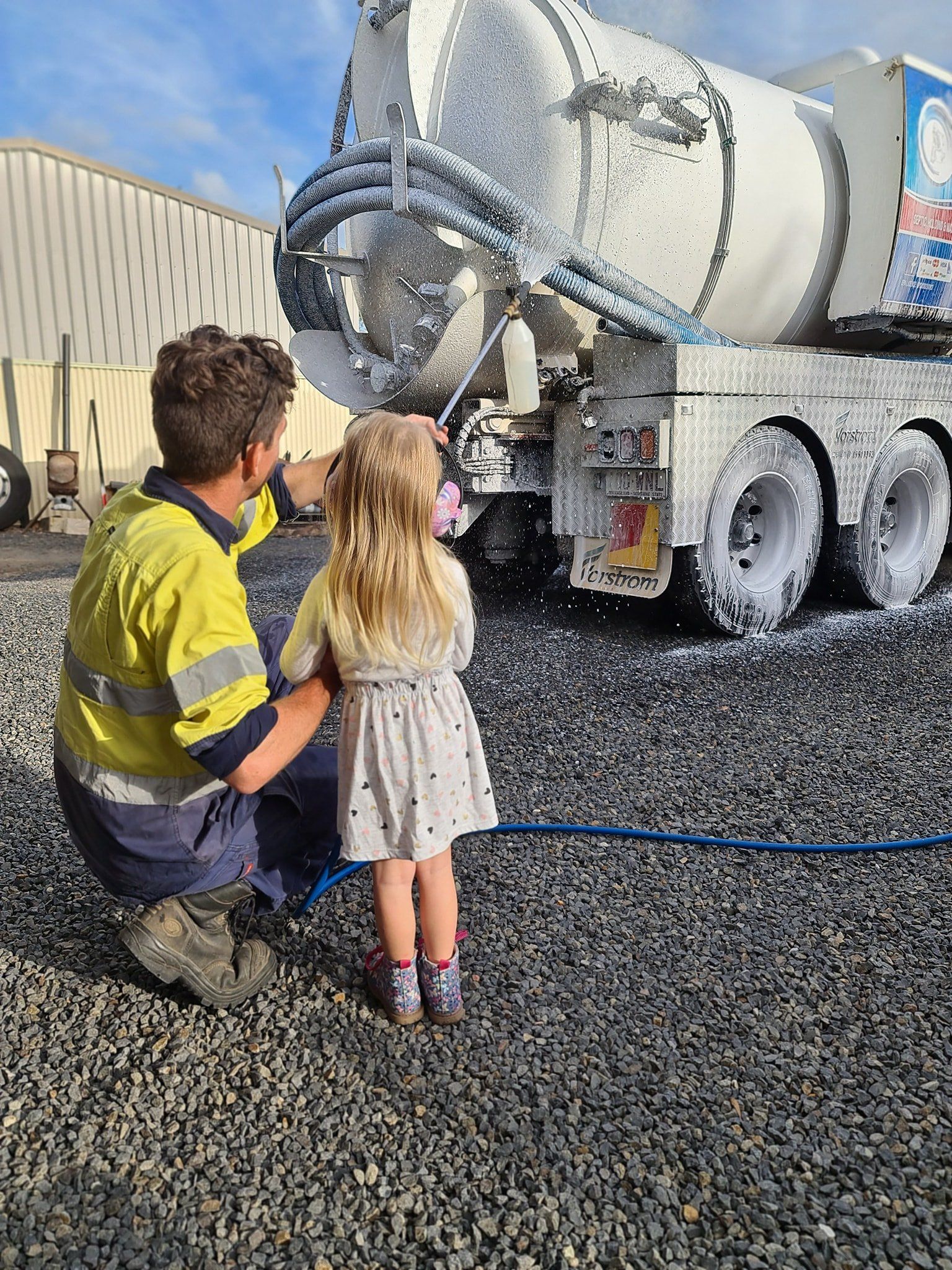 A Man And A Little Girl Are Standing In Front Of A Concrete Mixer Truck — Paap's Cleansing Services In Branyan, QLD
