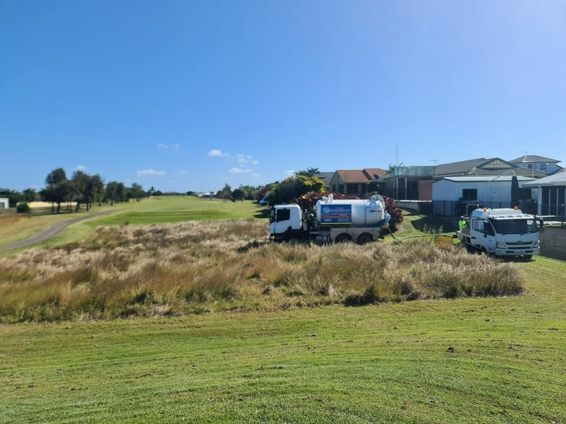 A White Truck Is Parked In A Grassy Field Next To A House — Paap's Cleansing Services In Bundaberg, QLD
