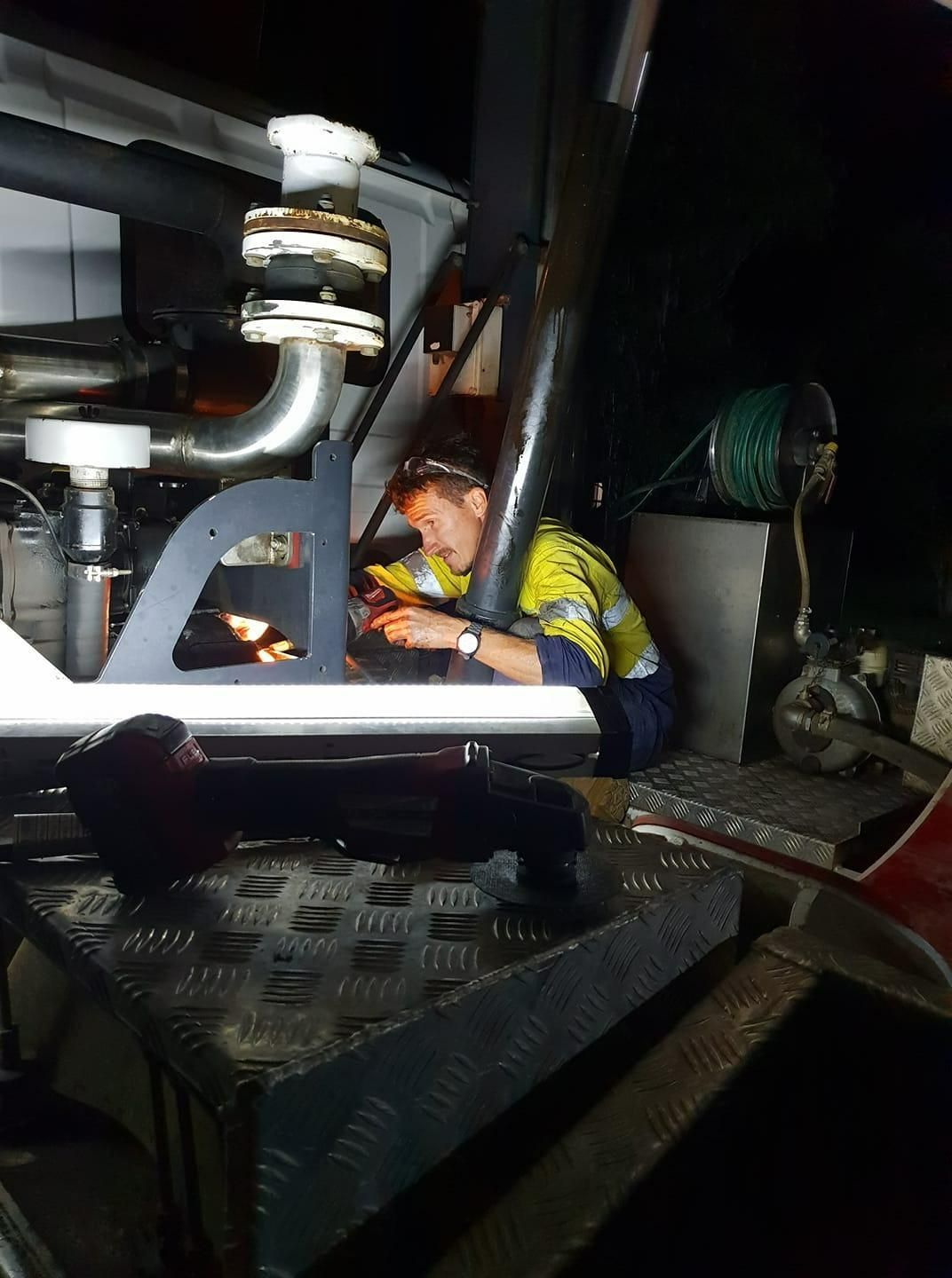 A Man Is Working On A Machine At Night — Paap's Cleansing Services In Gin Gin, QLD
