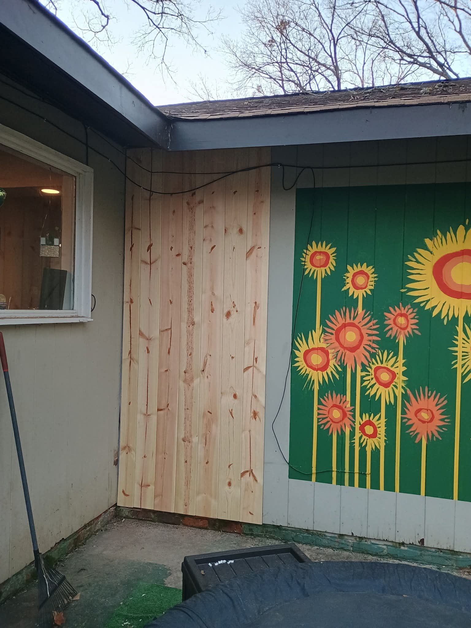 A wooden wall with a painting of sunflowers on it