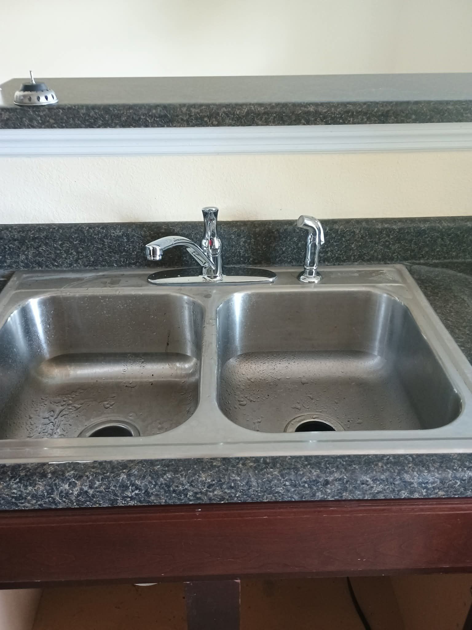 A stainless steel kitchen sink with a granite counter top