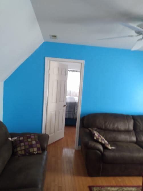 A living room with blue walls and a black couch