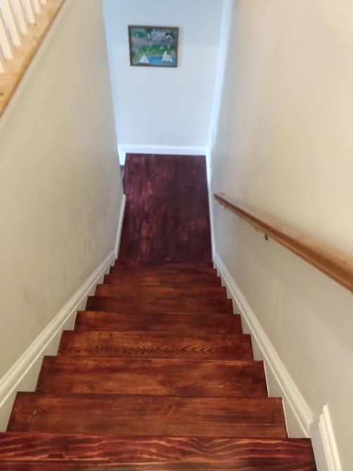 A wooden staircase with a picture on the wall above it