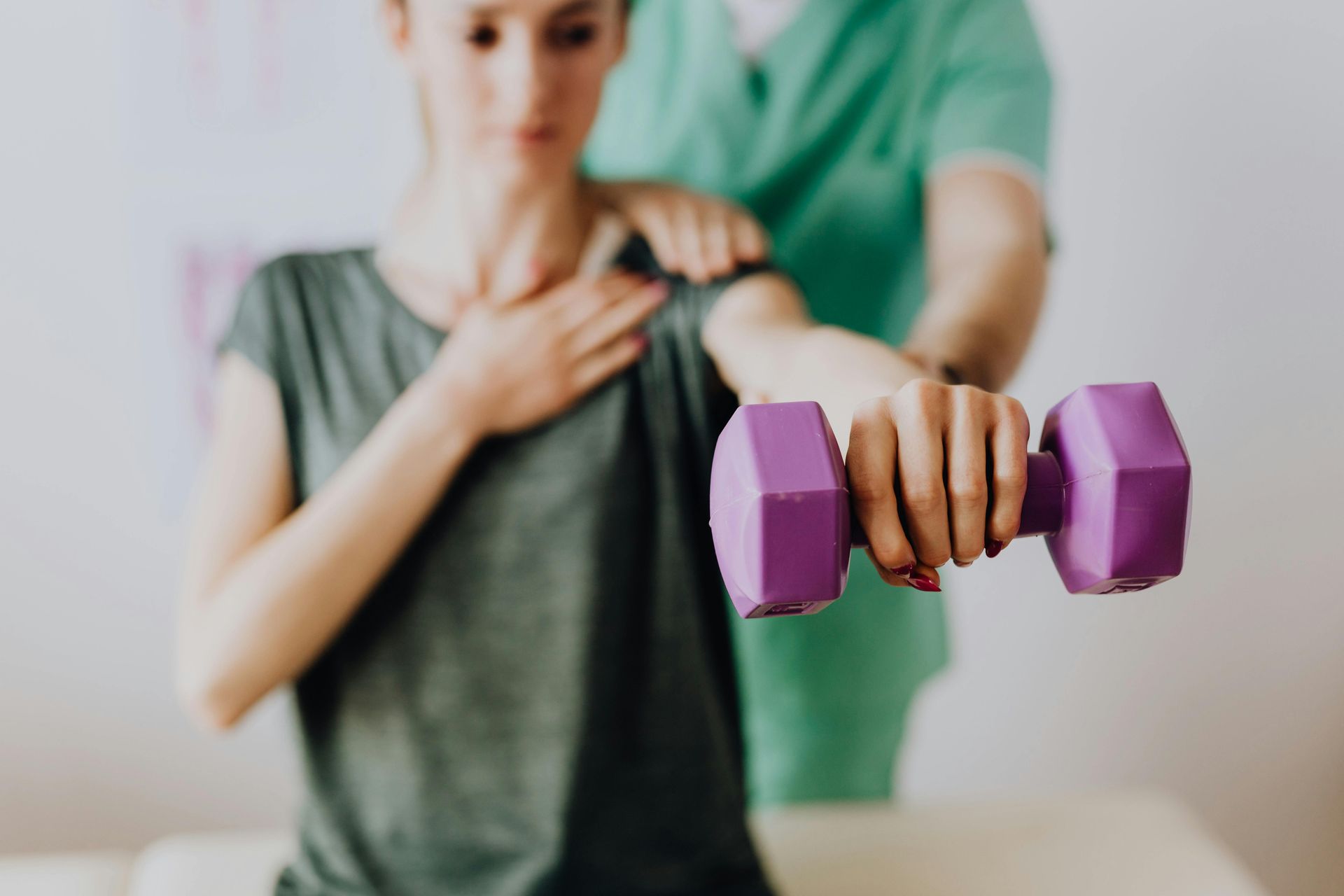 Photo of a woman holding a dumbbell while being massage by a chiropractor