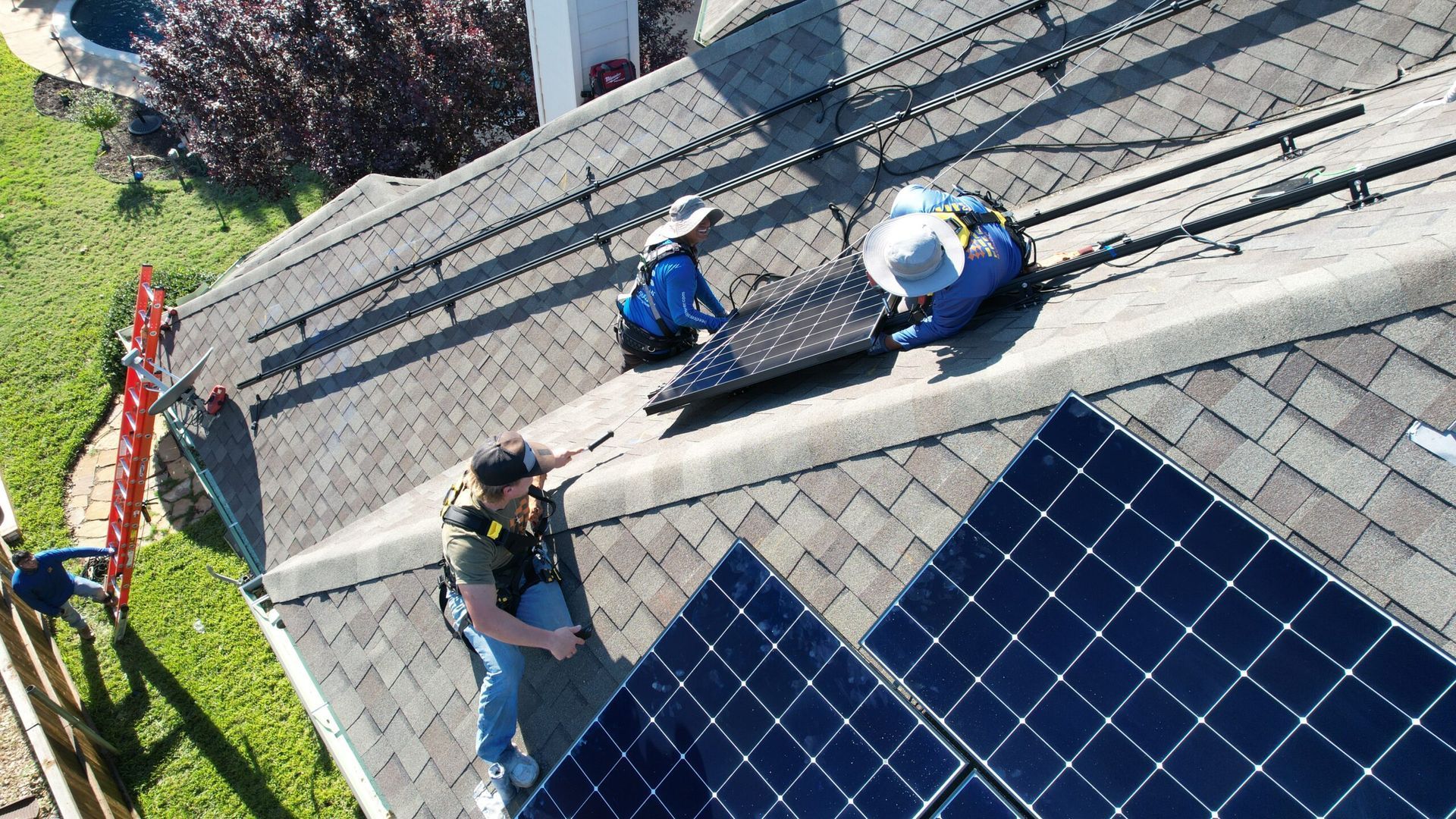Workers installing solar panels on a rooftop, wearing safety gear