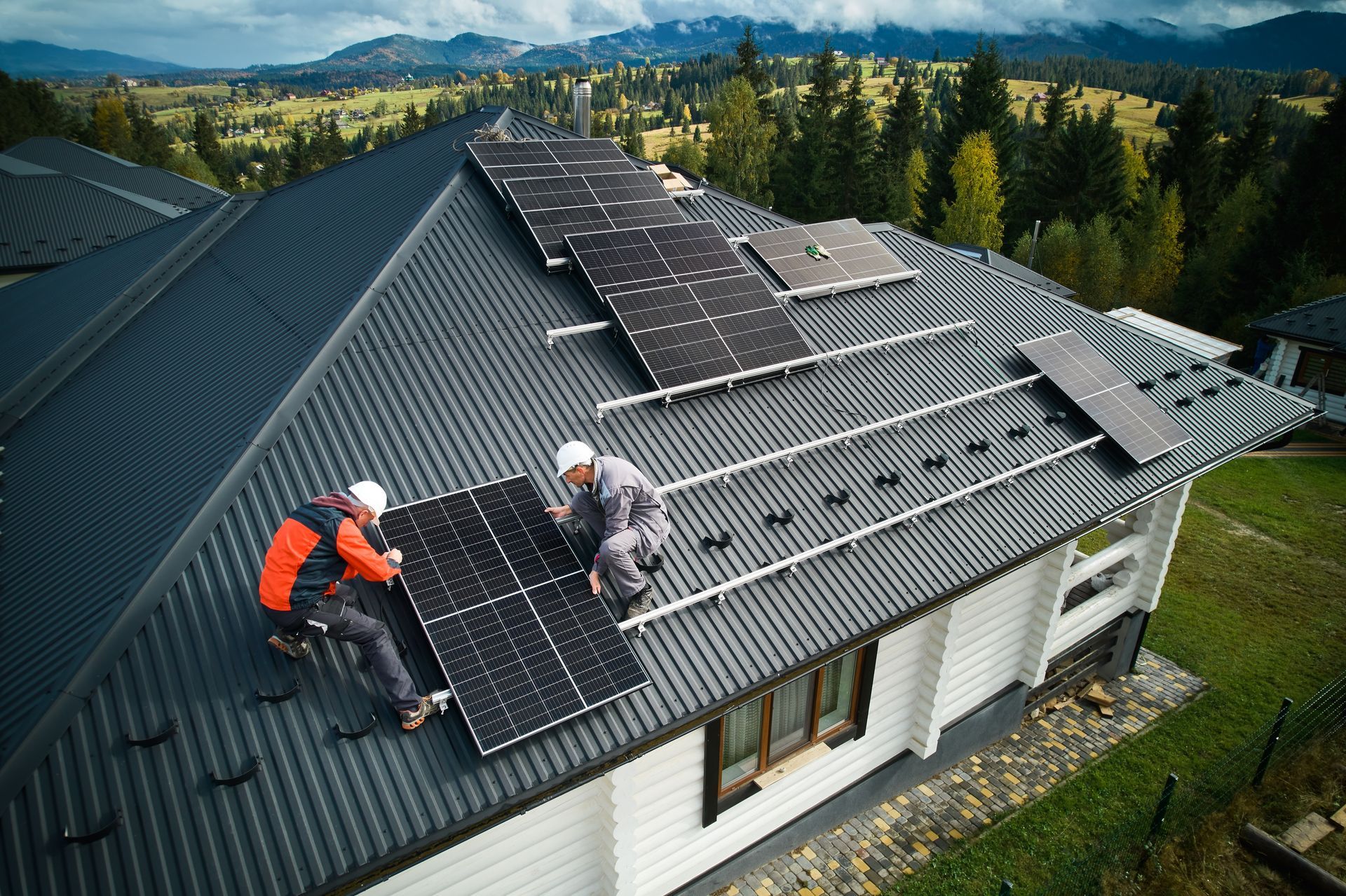 Workers installing solar panels on a black rooftop