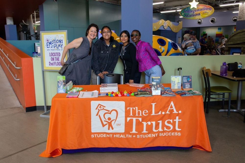 Four people standing behind a table with an orange