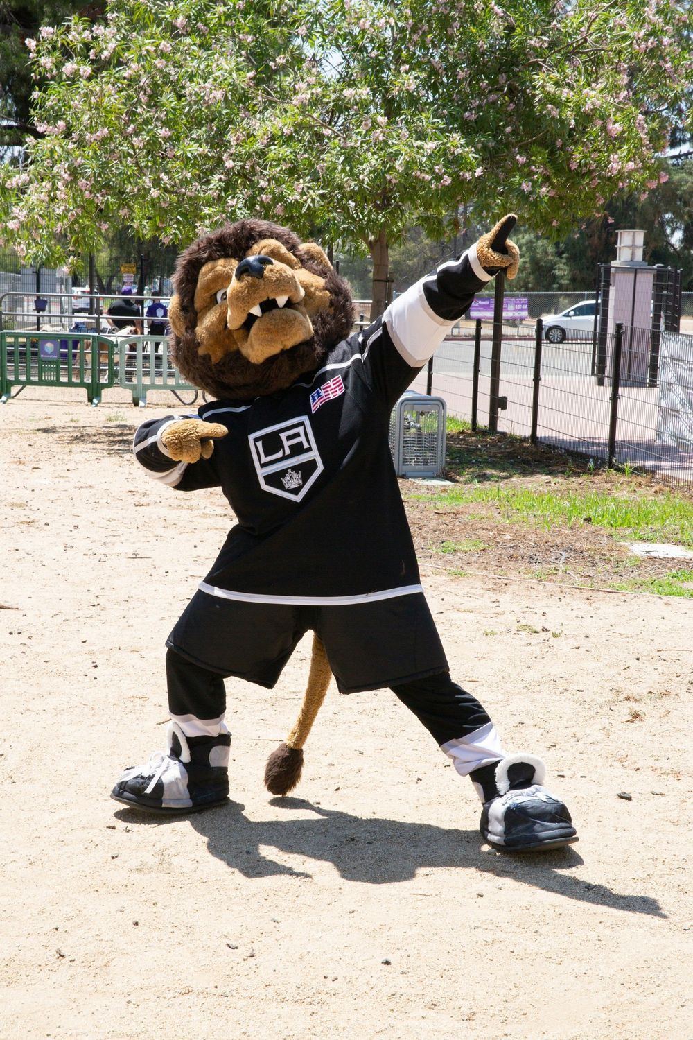 LA Kings mascot Bailey, a lion, wearing hockey gear dabs outdoors.