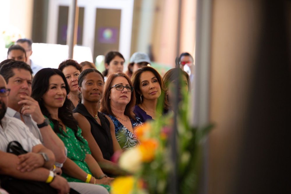 People seated, attentively watching something outdoors, possibly a ceremony.