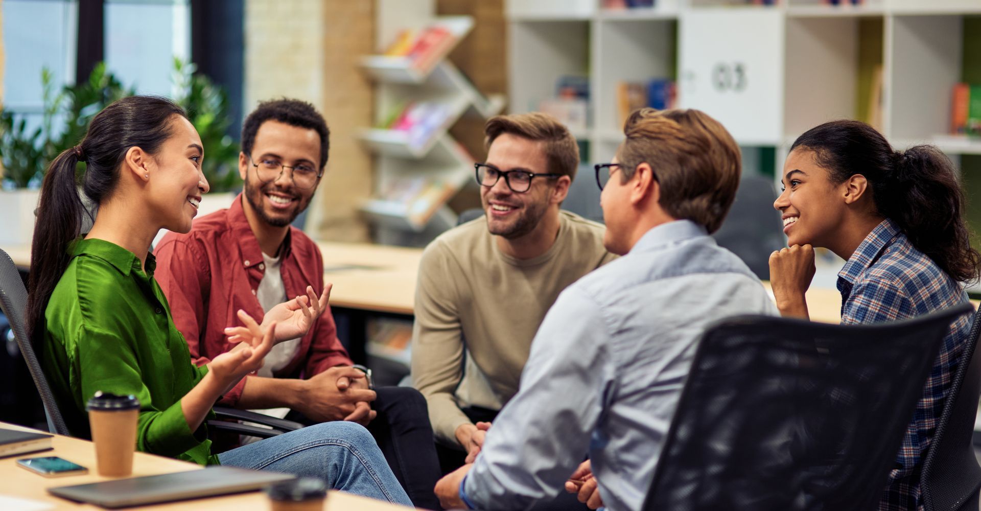 Group of people in an office setting, smiling and engaged in conversation.