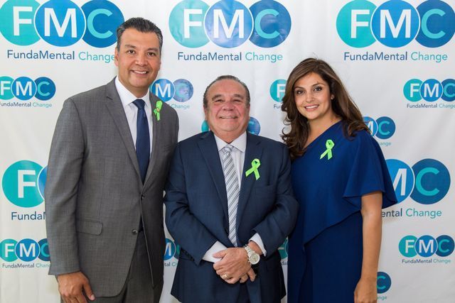 Three people posing in front of a backdrop with the 