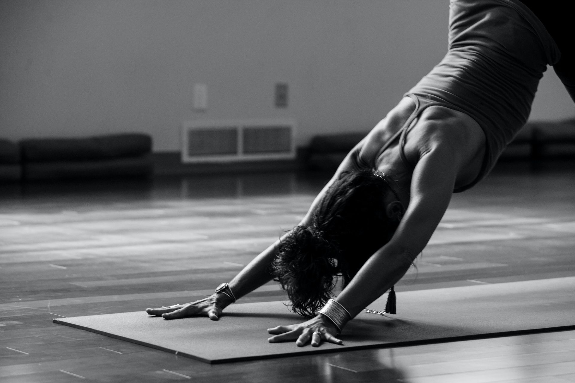 Person in downward-facing dog yoga pose on a mat in a studio.