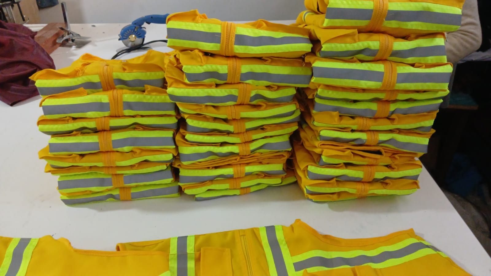 Montones de chalecos reflectantes de seguridad amarillos y verde neón doblados sobre una mesa.