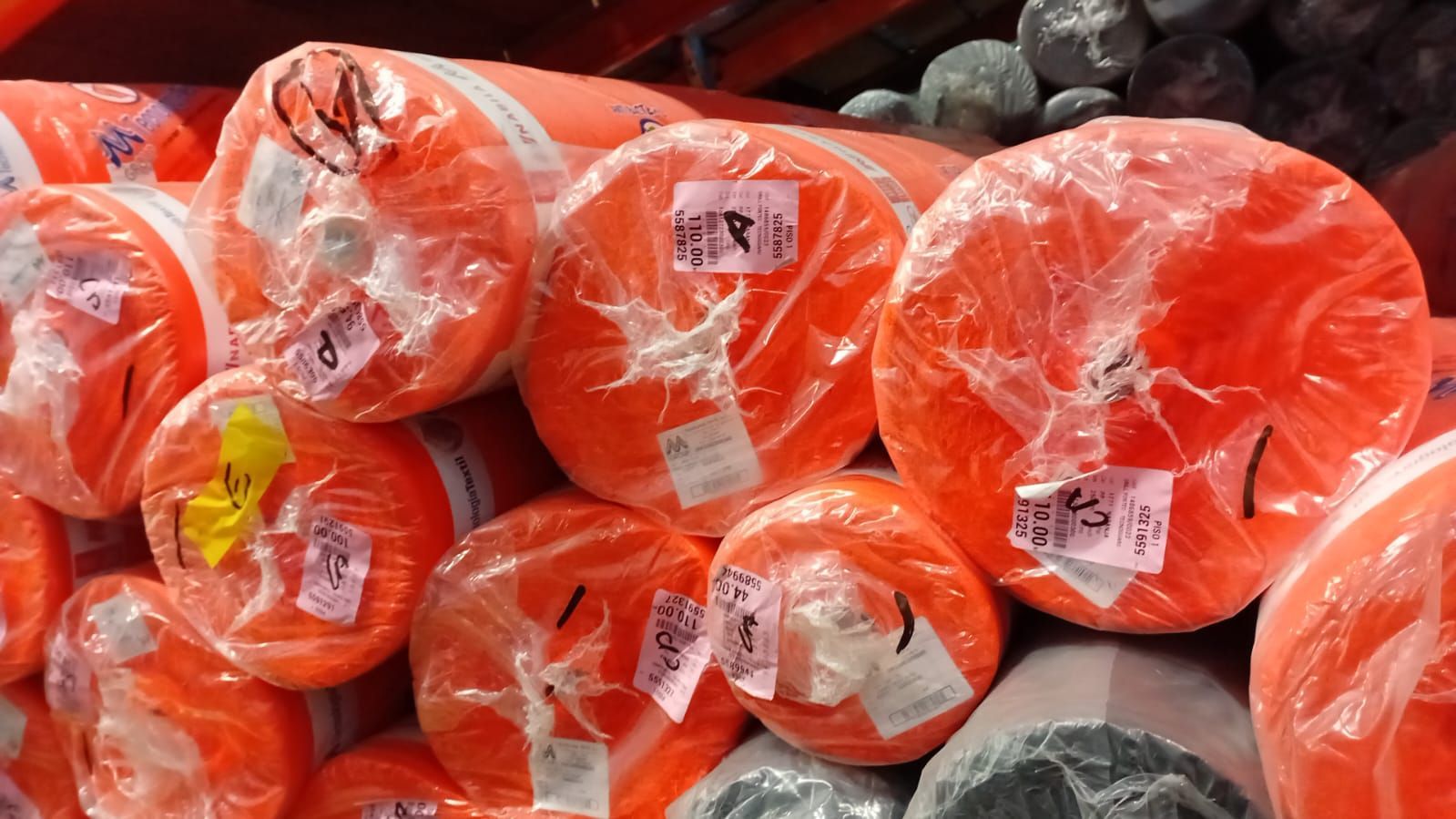 Pilas de tubos de plástico enrollados de color naranja brillante envueltos en plástico transparente.