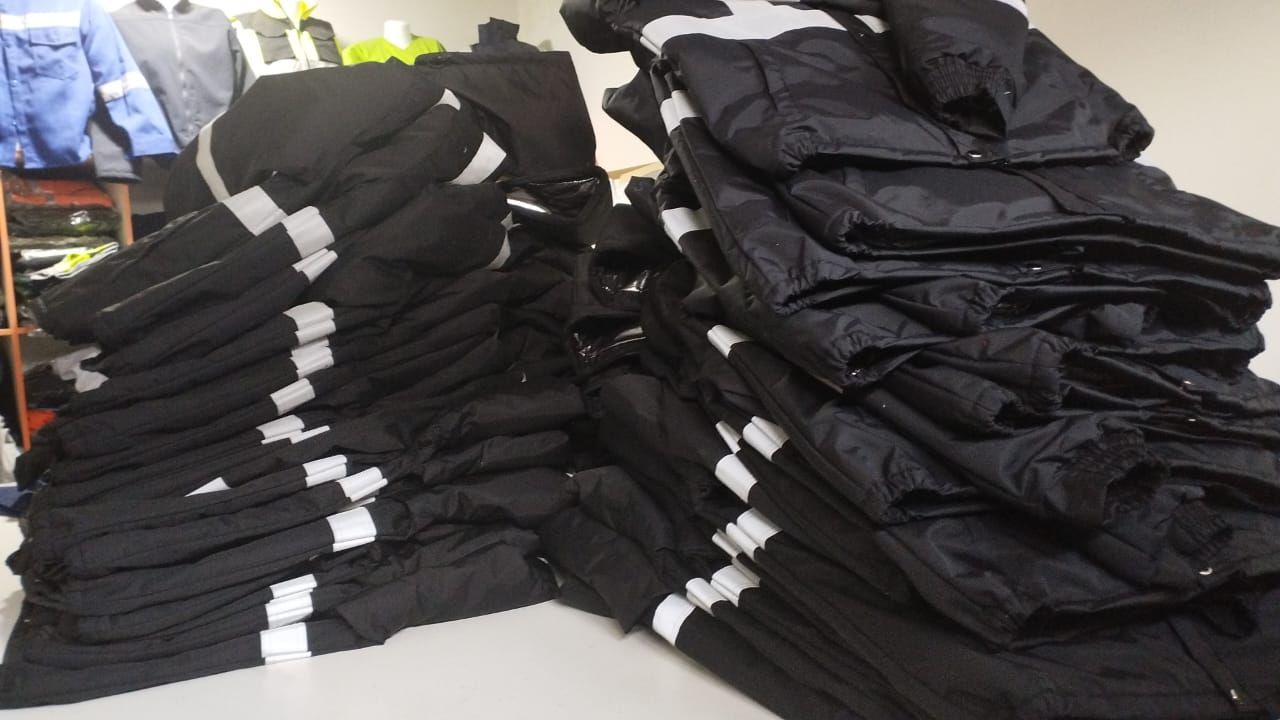 Montones de pantalones negros doblados con rayas blancas sobre una mesa en una tienda de ropa.