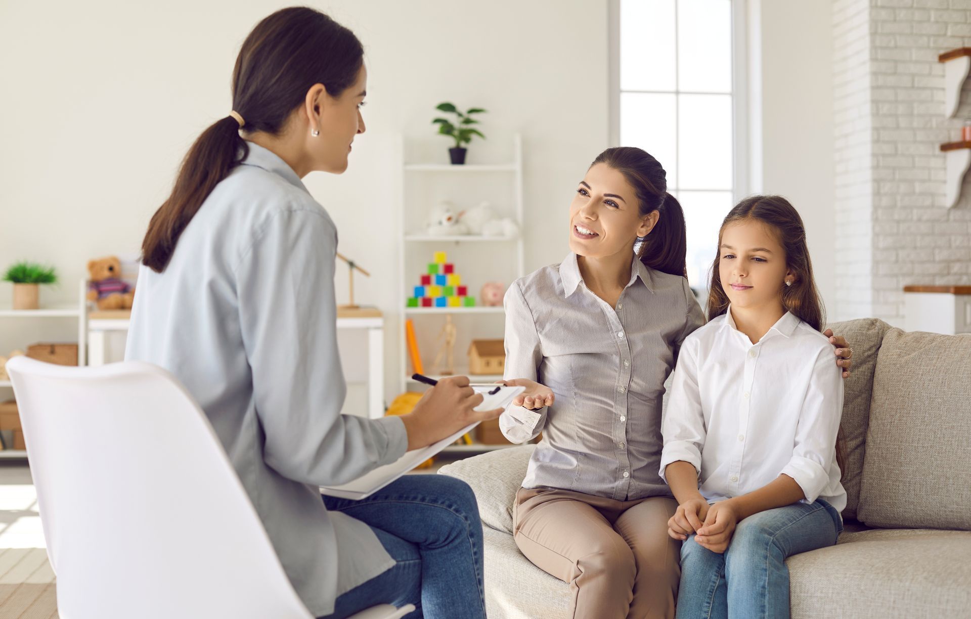 Mother and daughter in session with a child family counselor discussing emotions and behavior.