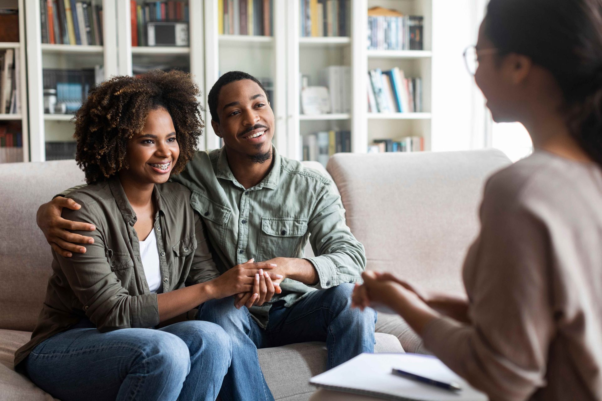 A couple in a therapy session with a counselor holding notes in a cozy living room.