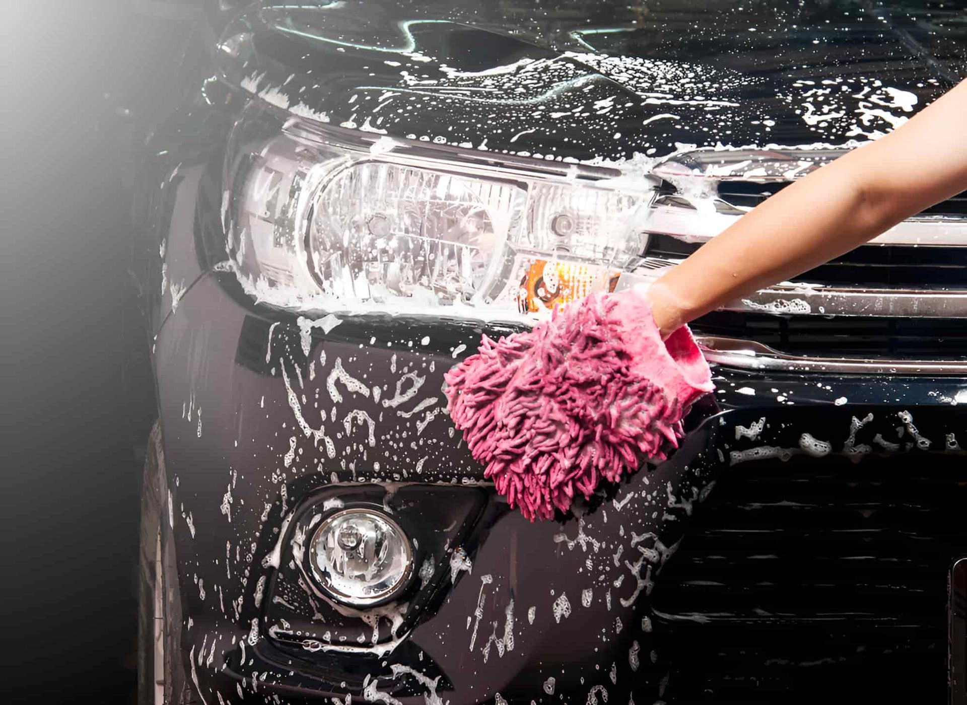 A Person Is Washing A Car With A Pink Glove — Country Dirt Blasters Mobile Car Detailing In Murwillumbah, NSW