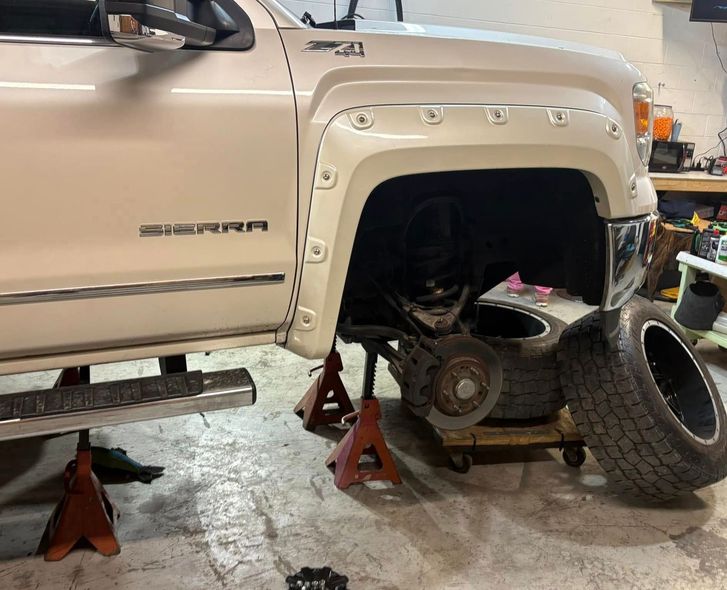 A white truck is being worked on in a garage.