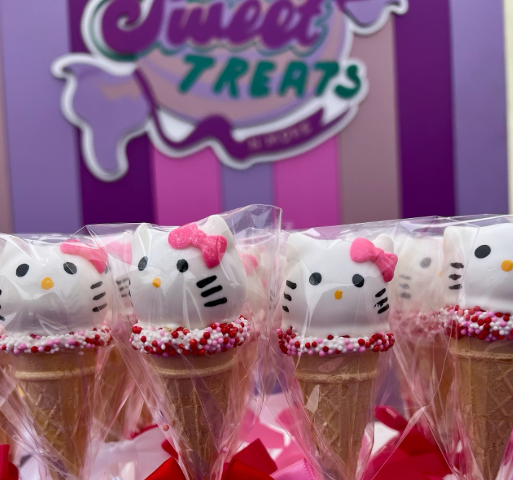 A row of hello kitty ice cream cones in front of a sign that says sweet treats