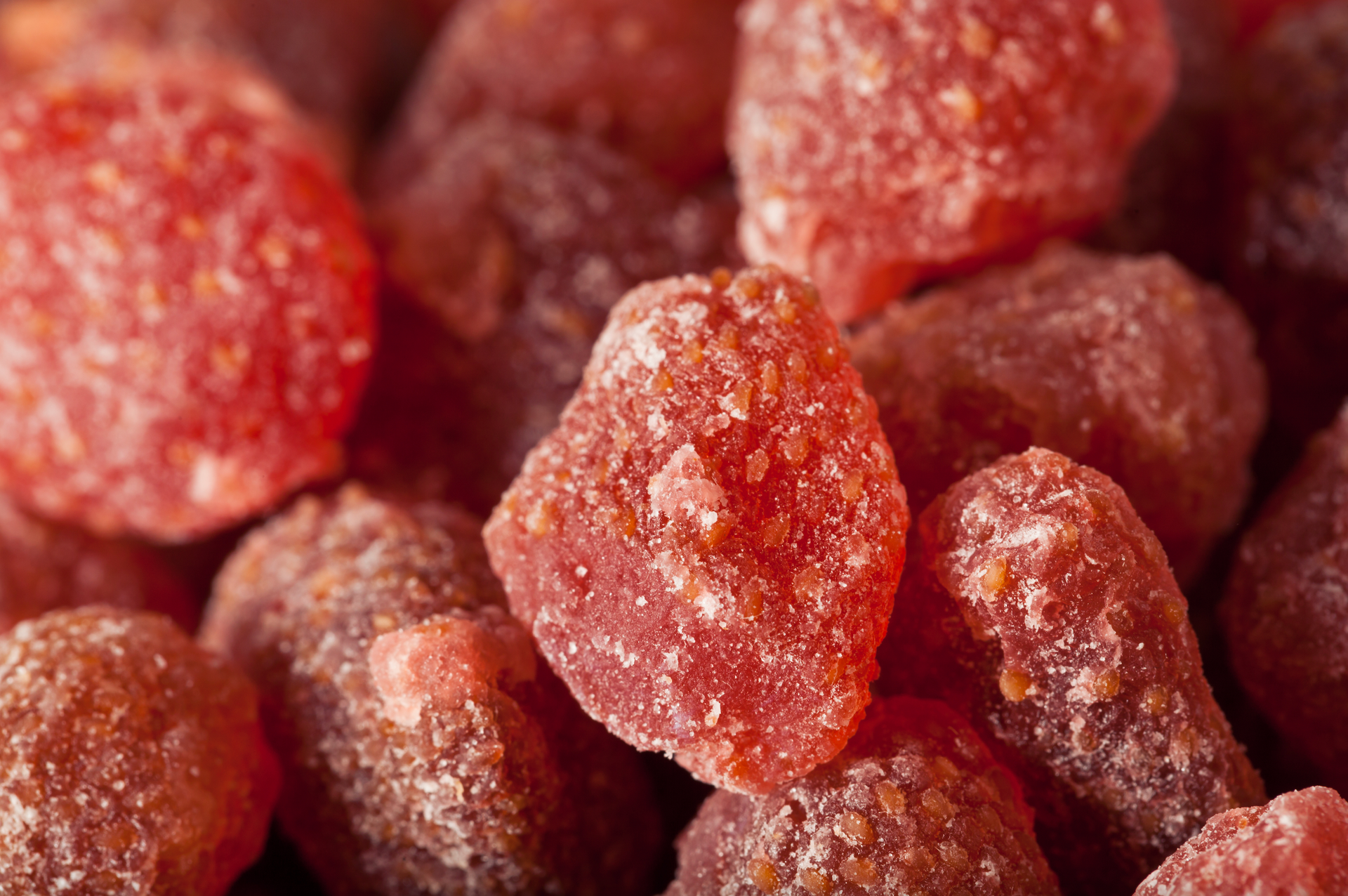 A close up of a pile of dried strawberries covered in sugar.