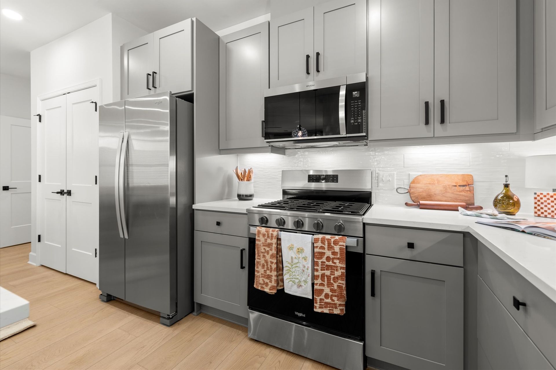 A kitchen with stainless steel appliances and gray cabinets.