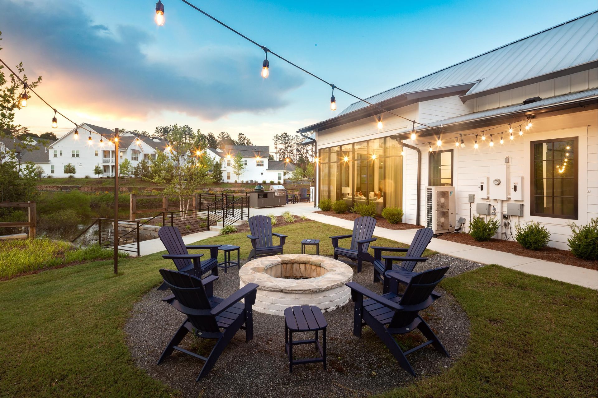 There is a fire pit in the middle of the yard with chairs around it.