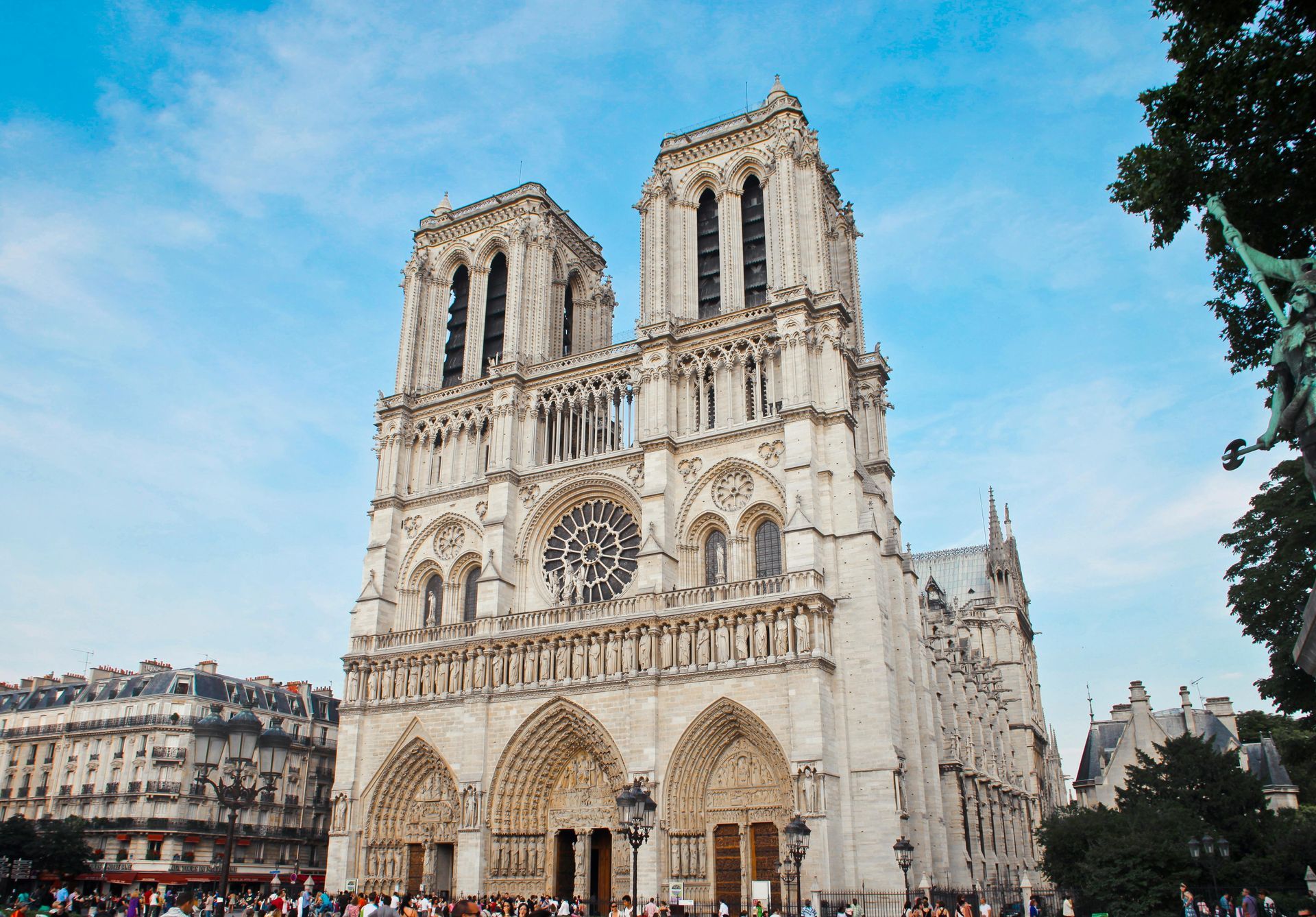 Notre Dame Cathedral, Paris, France, with twin towers and ornate facade under a blue sky.
