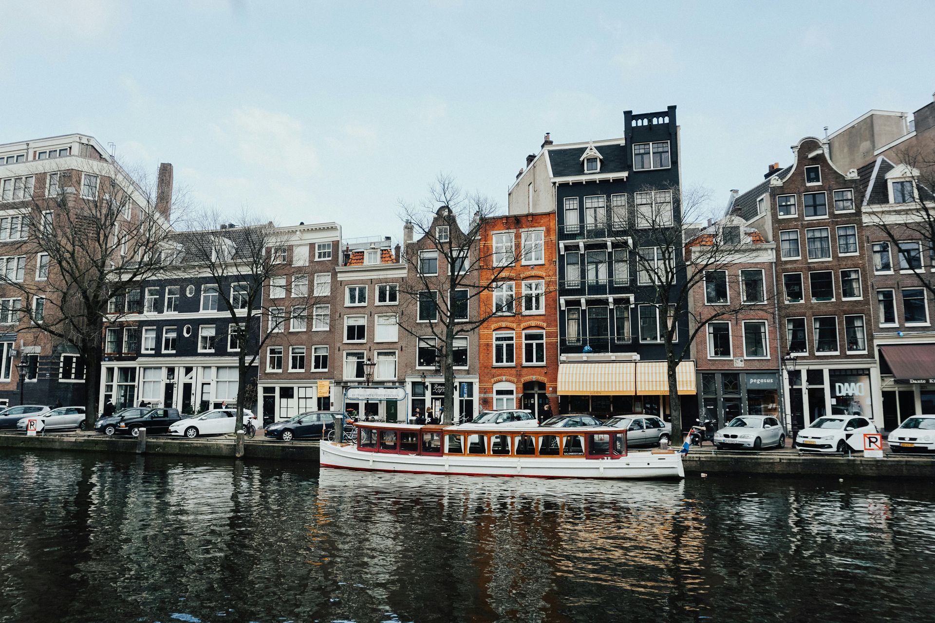 Canal in Amsterdam with colorful buildings and a tour boat.