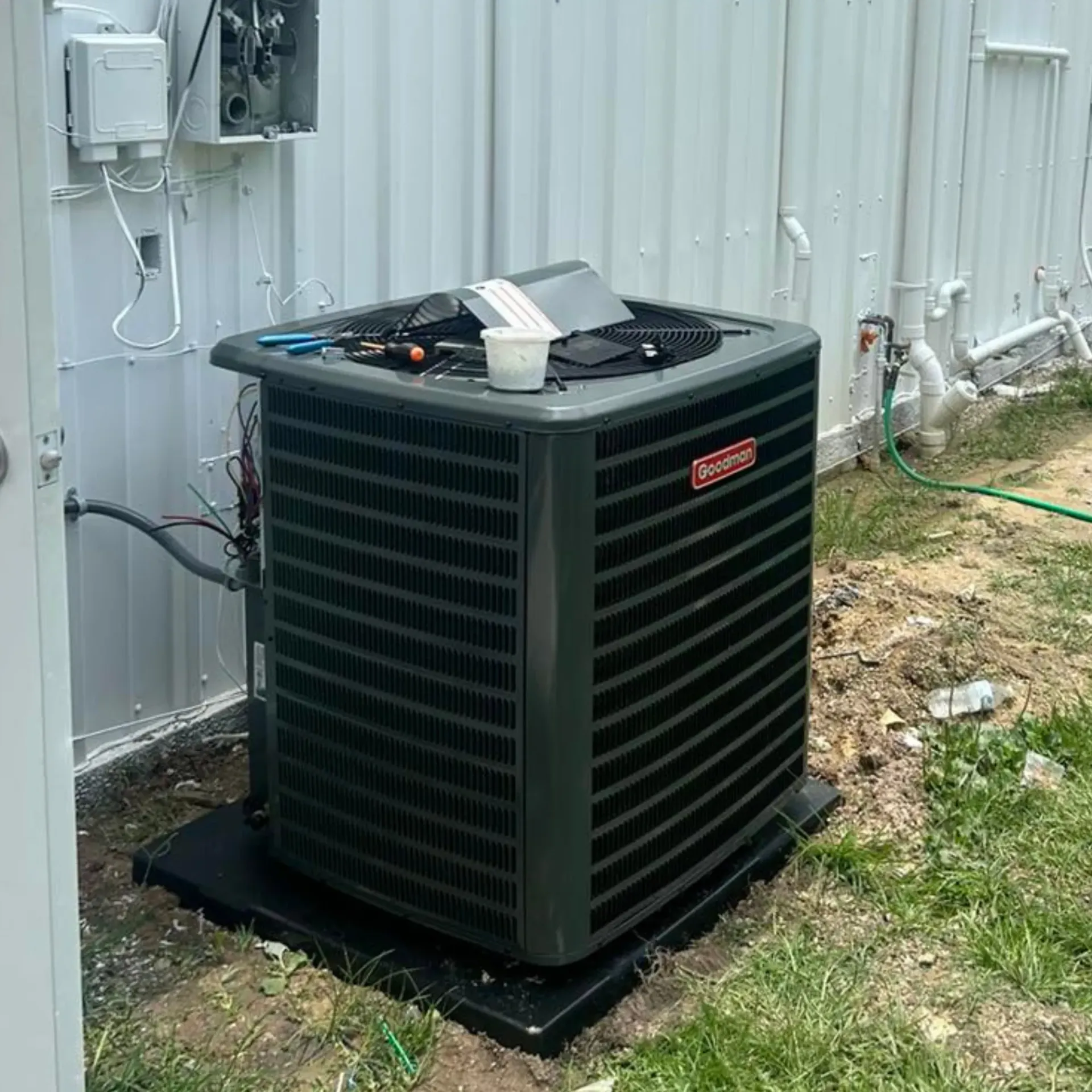 Flawless Heating and Air LLC - An air conditioner is sitting in the grass next to a fence.