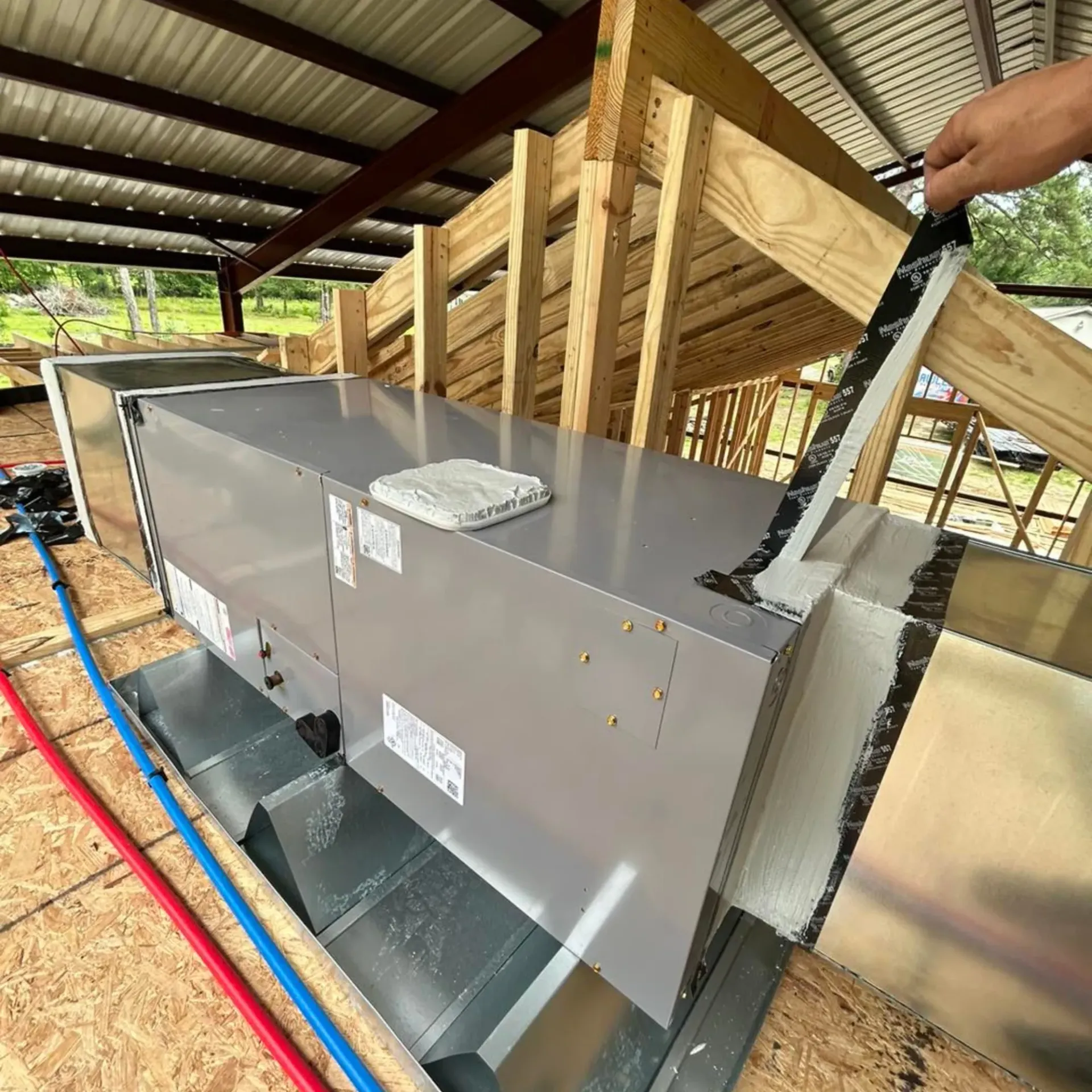 Flawless Heating and Air LLC - A person is applying tape to a metal box in a building under construction.