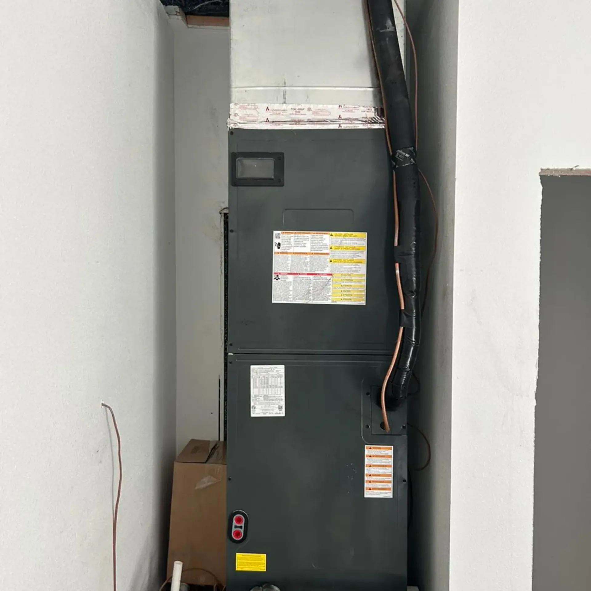 Flawless Heating and Air LLC - A black air conditioner is sitting in a corner of a room.