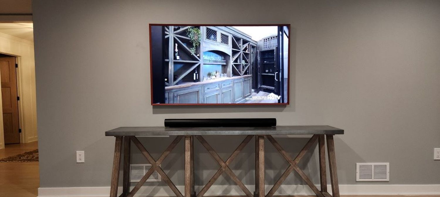 A flat screen tv is hanging on a wall above a wooden table.