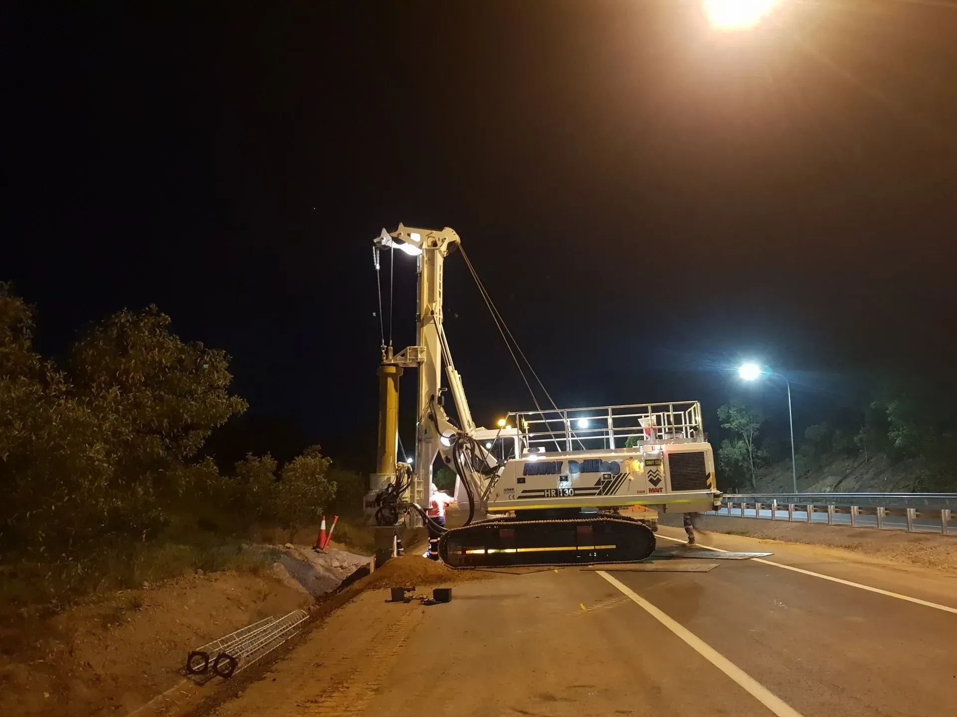 A construction vehicle is parked on the side of a road at night.