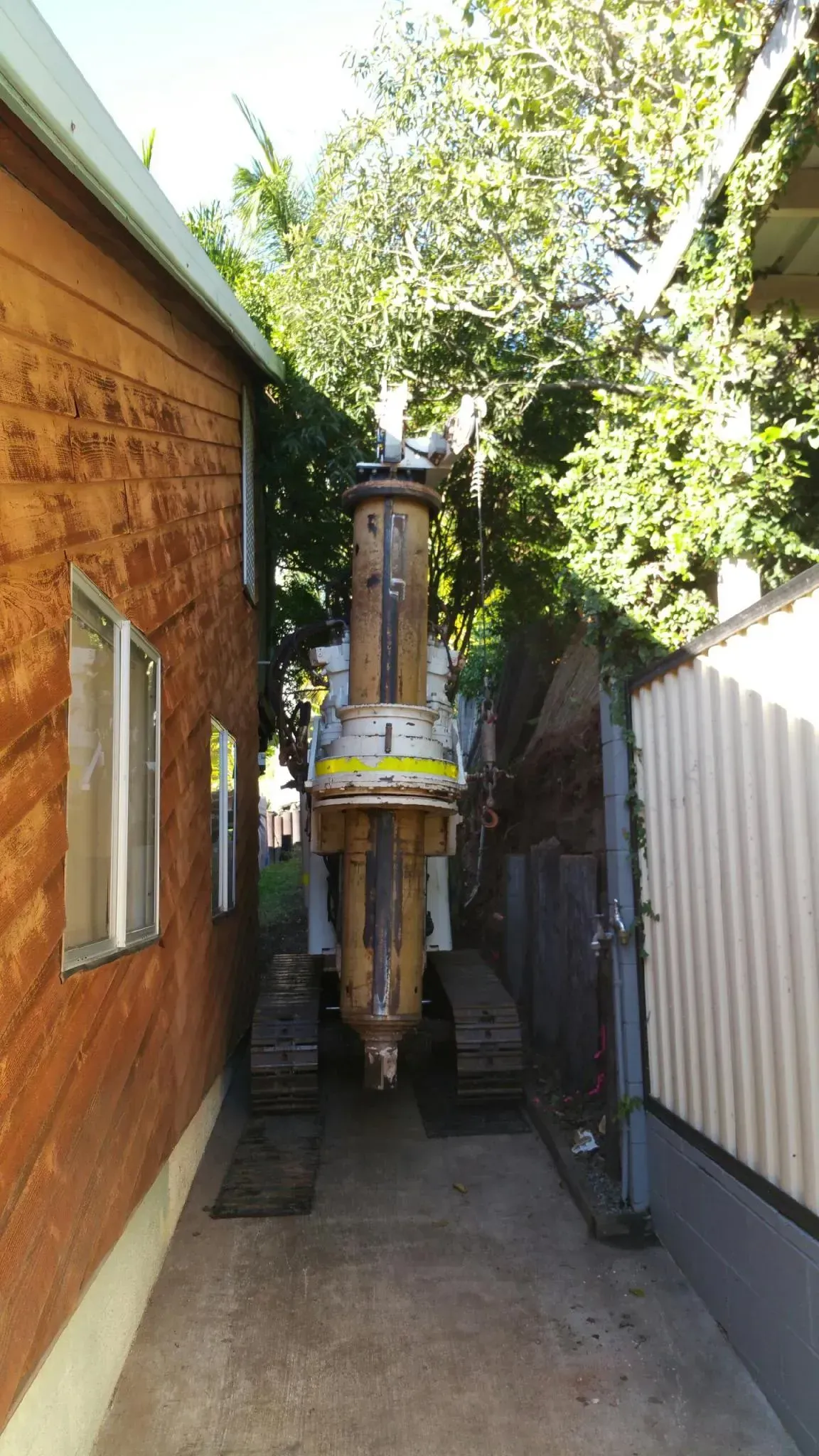 A large machine is parked in a narrow alleyway between two buildings.