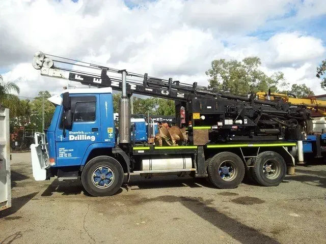 A blue drilling truck is parked in a parking lot
