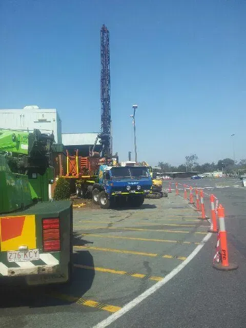 A truck is parked in a parking lot next to a crane.