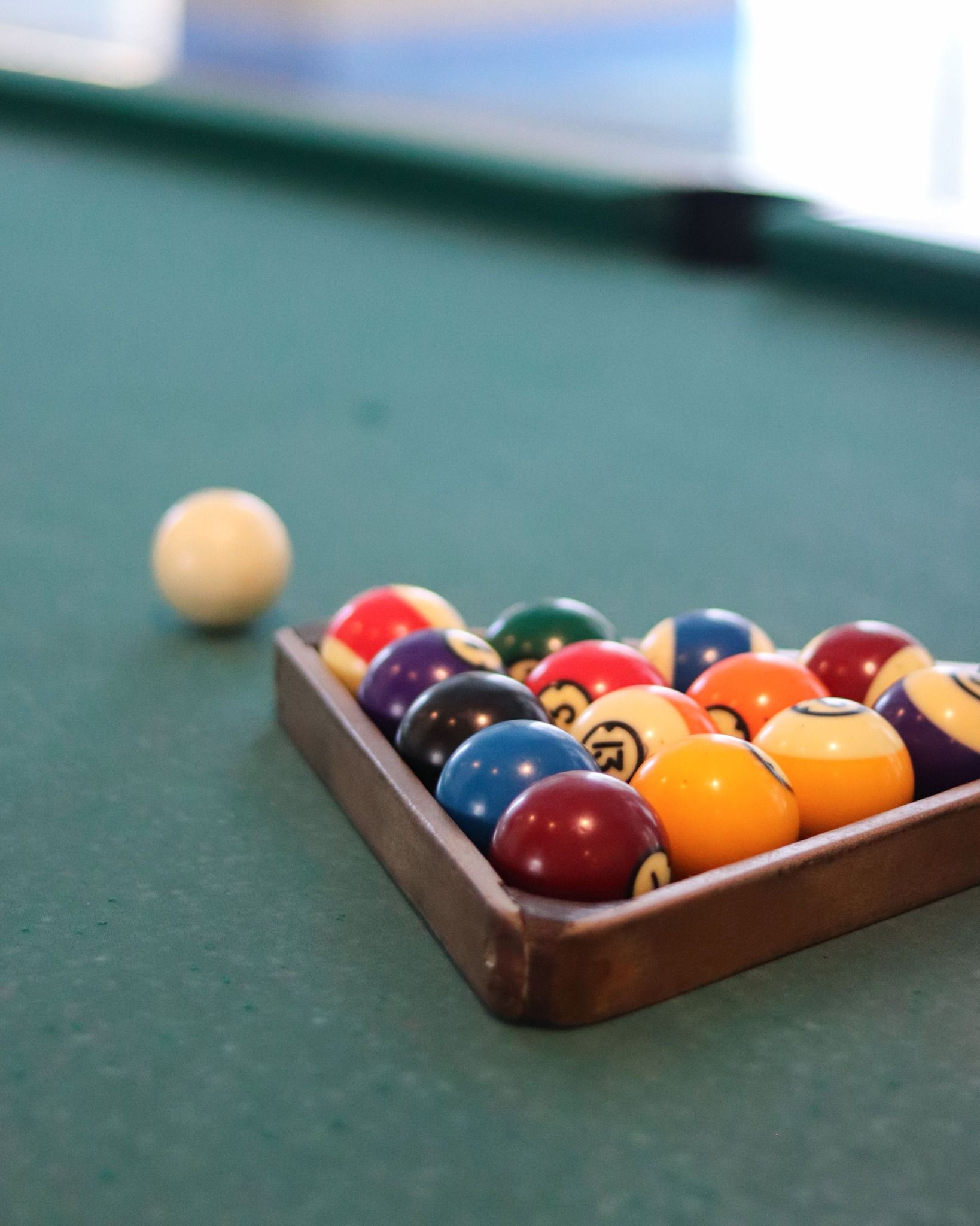 Pool balls racked in a triangle, with cue ball to the side, on a green felt pool table.