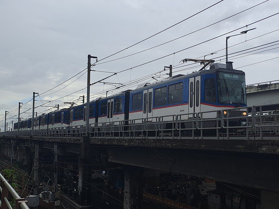A blue and white train is going over a bridge.